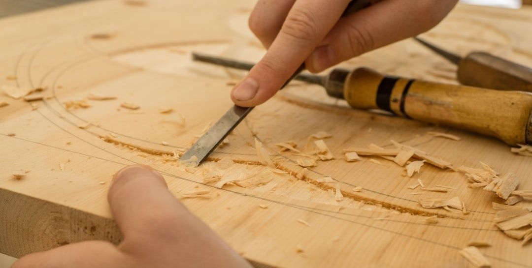 Handen bewerken een houten plank met een beitel in een werkplaats